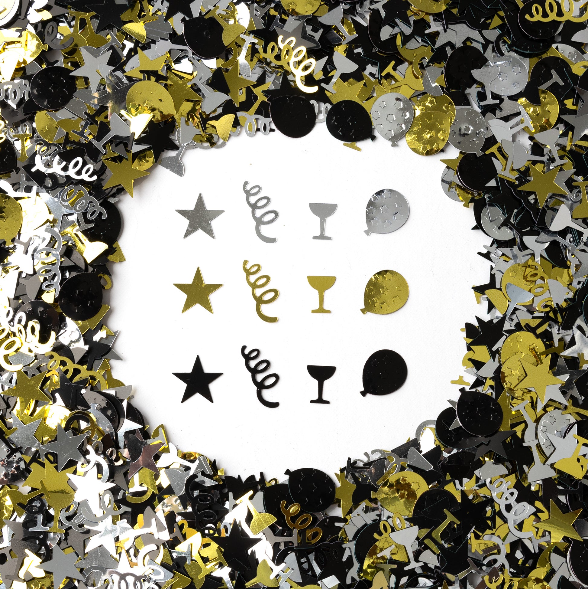 Metallic black, gold, and silver celebration confetti with stars, spirals, champagne glasses, and mixed shapes scattered on a white background