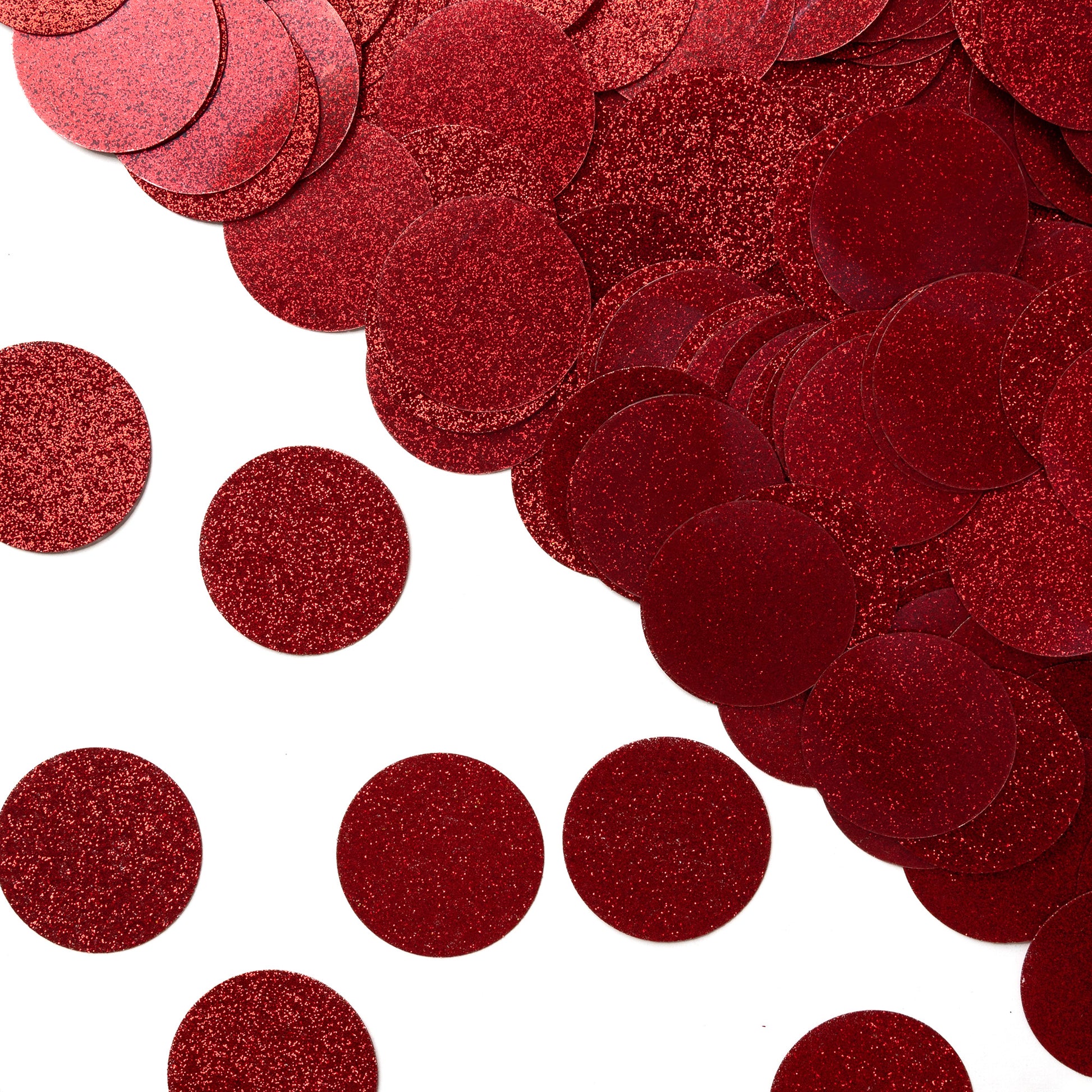 Luxe red glitter circle confetti piled on one side and scattered on a white background
